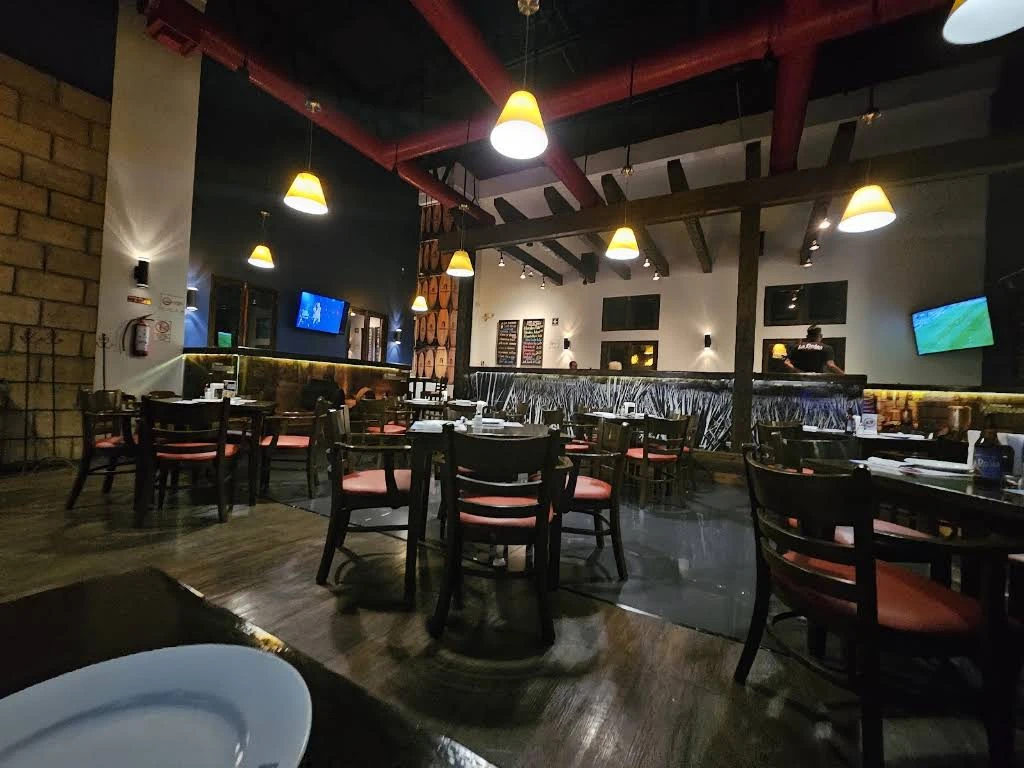 Mesas, madera y lámparas cálidas en el salón de Linda Vista
